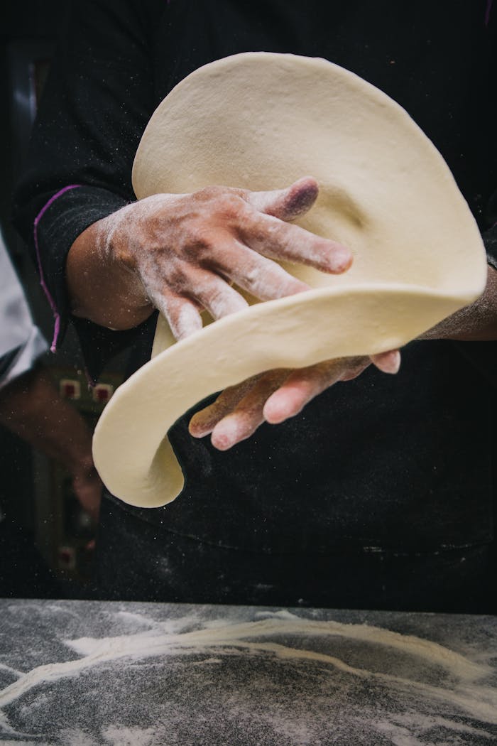 Close-up of chef tossing pizza dough in a kitchen, showcasing expert culinary skills.